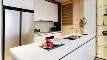 A modern kitchen with white cabinetry, a marble countertop, and a built-in oven.