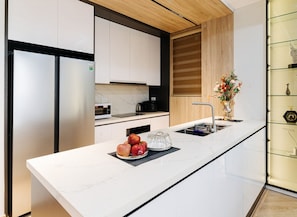 A modern kitchen with white cabinetry, a marble countertop, and a built-in oven. - Luxe Paradise Residence Dang Thai Mai (Hanoi)