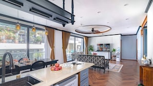 Una cocina moderna con una isla central, un comedor con una mesa de diseño blanco y negro, y vistas al balcón exterior.