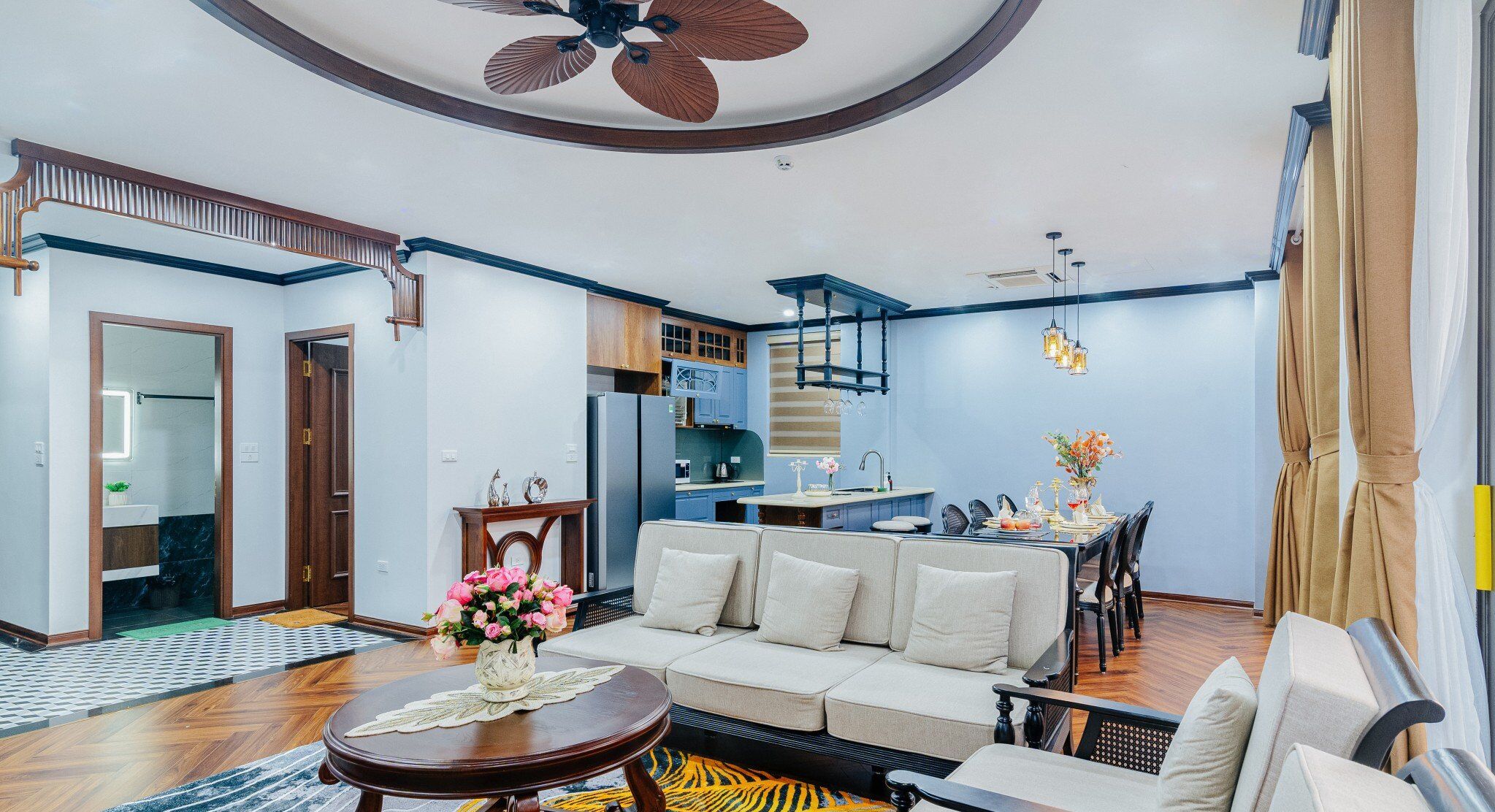 A spacious living area with a sofa, dining table, and a ceiling fan.