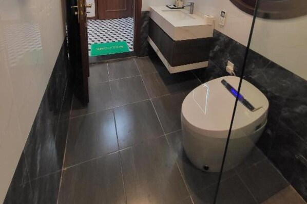 Un baño con inodoro, lavamanos y piso de baldosas.