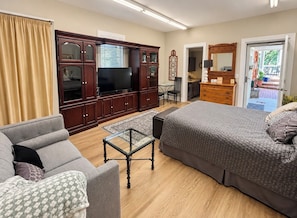 A furnished room with a sofa, a bed, a television, a cabinet, and a dining area.