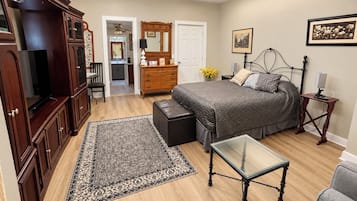 Une chambre à coucher comprenant un lit, une commode, un téléviseur, une table basse en verre et un tapis.
