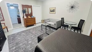 Une chambre à coucher comprenant un lit, une commode, un canapé, une table basse et un fauteuil.