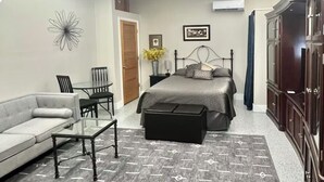 Une chambre à coucher comprenant un lit, un canapé, une table basse, un tapis, une commode et un tableau au mur.