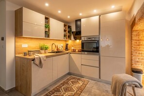 A compact kitchen with wooden cabinetry, a built-in stove, and a small seating area. - Rijeka City Vibes Apartment, Rijeka, Croatia (Rijeka)