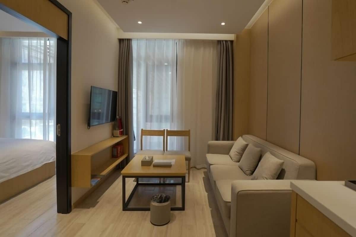 Ein modernes Hotelzimmer mit einem Bett, einer Couch, einem Couchtisch und einem Fernseher.