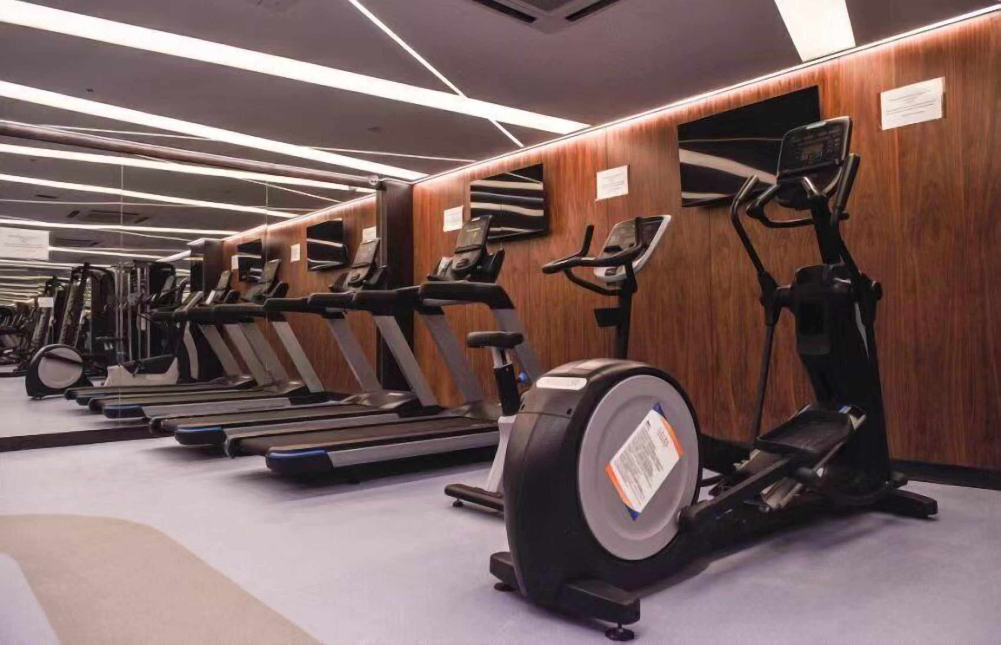 A gym with multiple treadmills and elliptical machines.
