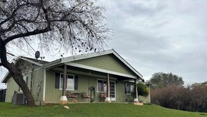 Una casa de un piso con techo inclinado, un porche cubierto y una antena parabólica.