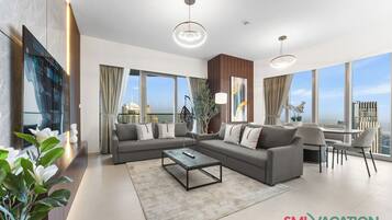 A modern living room with a sofa, coffee table, and dining area, large windows with a city view, and a plant.