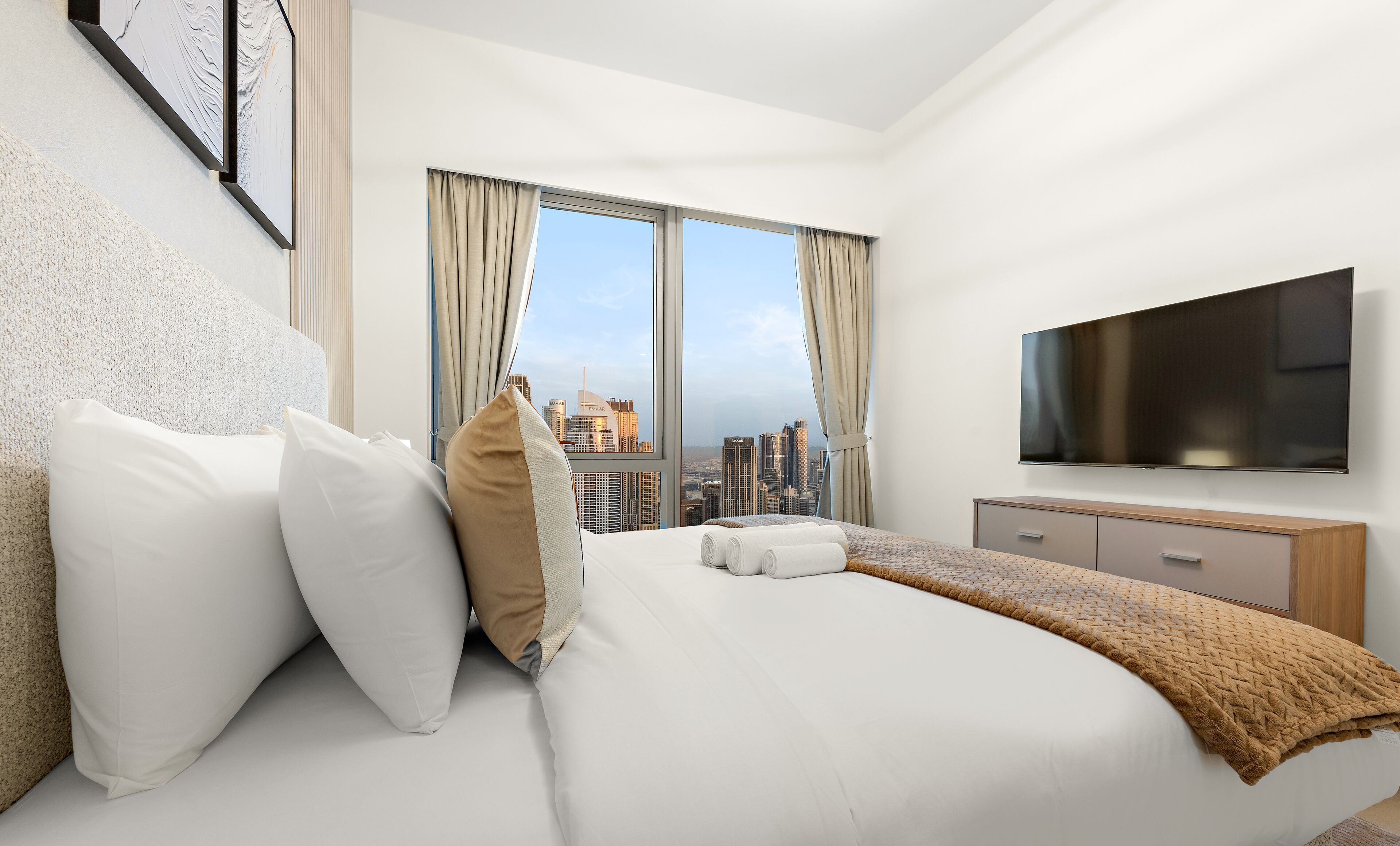 A hotel room with a large bed, a TV, and a city view.