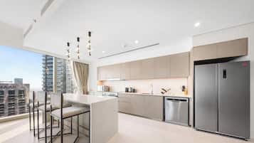 A modern kitchen with a stainless steel refrigerator, a built-in oven, and a large window overlooking a cityscape.