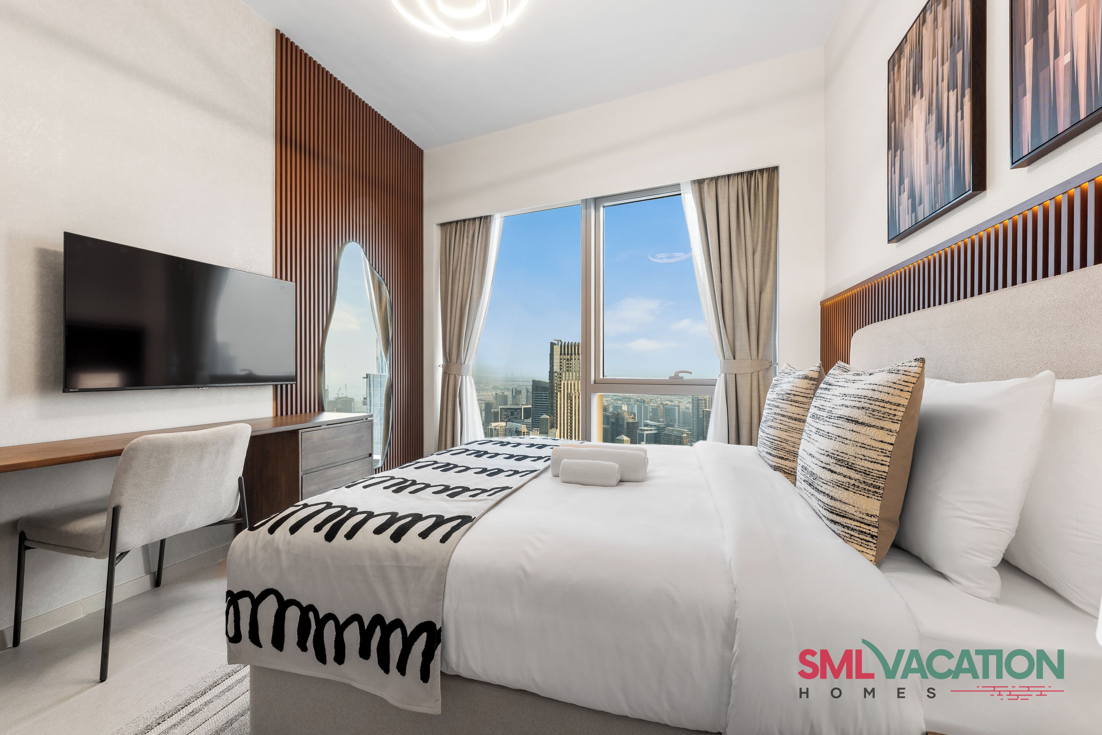 A modern hotel room with a large bed, a flat-screen TV, a desk, and a city view.