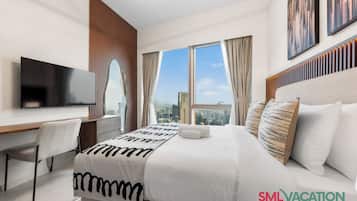 A modern hotel room with a large bed, a flat-screen TV, a desk, and a city view.
