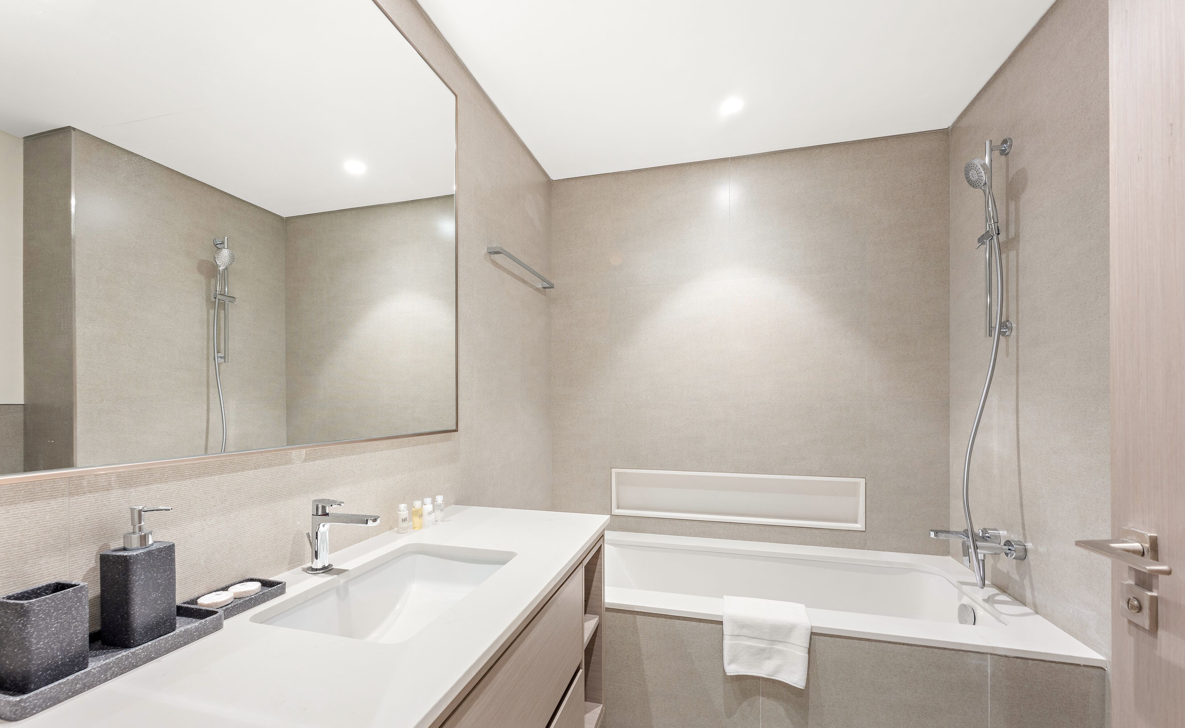 A modern bathroom with a large mirror, a sink, a bathtub, and a shower.