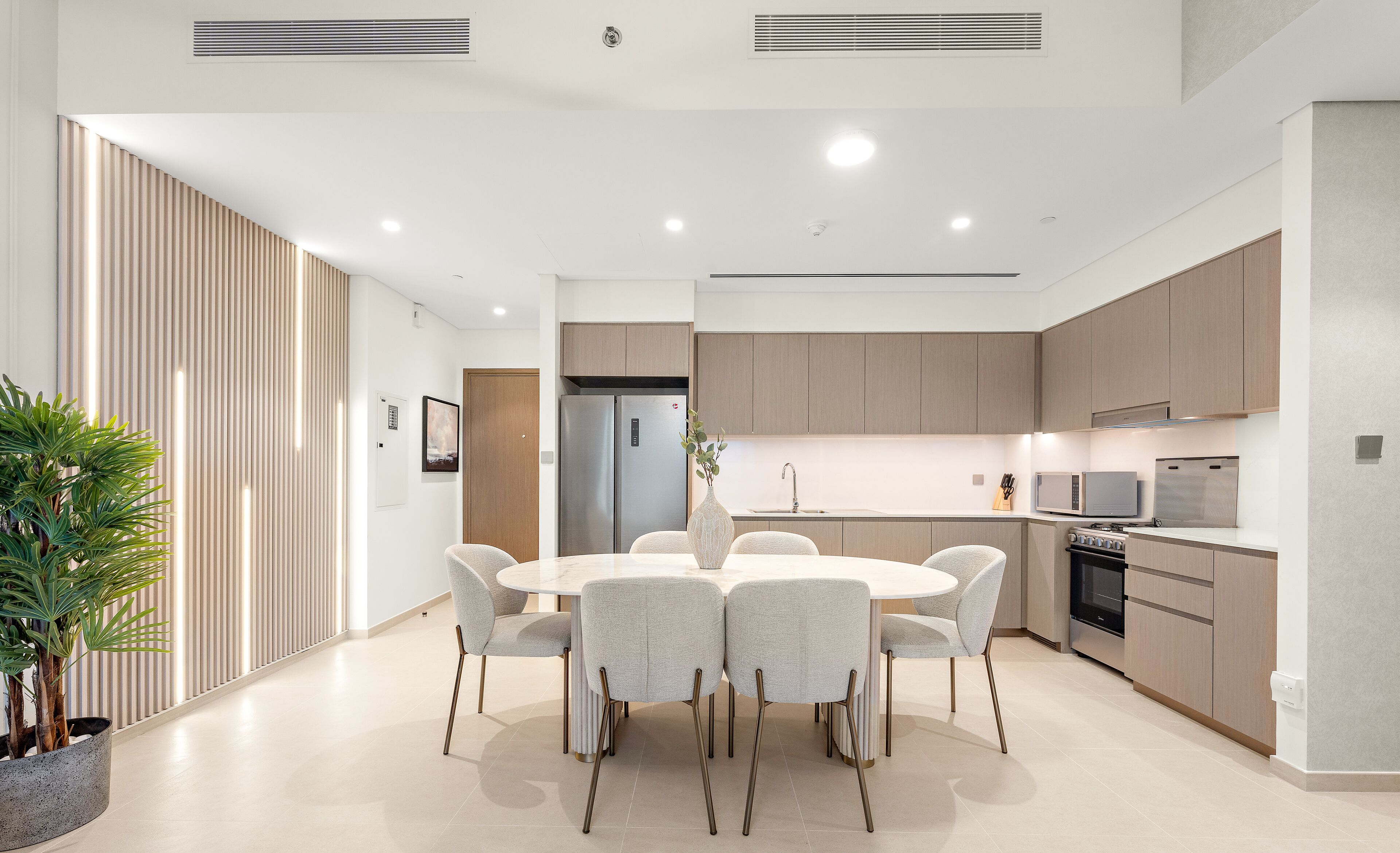 A modern kitchen with a dining area, featuring a central island, built-in appliances, and a minimalist design.
