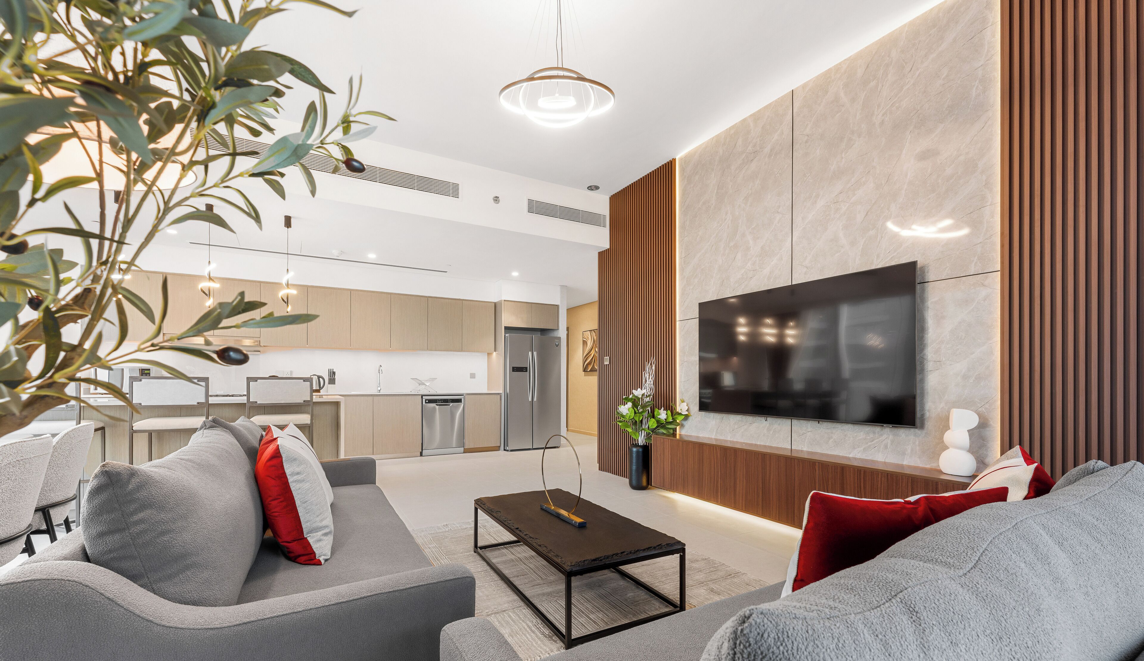 A modern living room with a sofa, coffee table, and a flat-screen TV mounted on the wall.