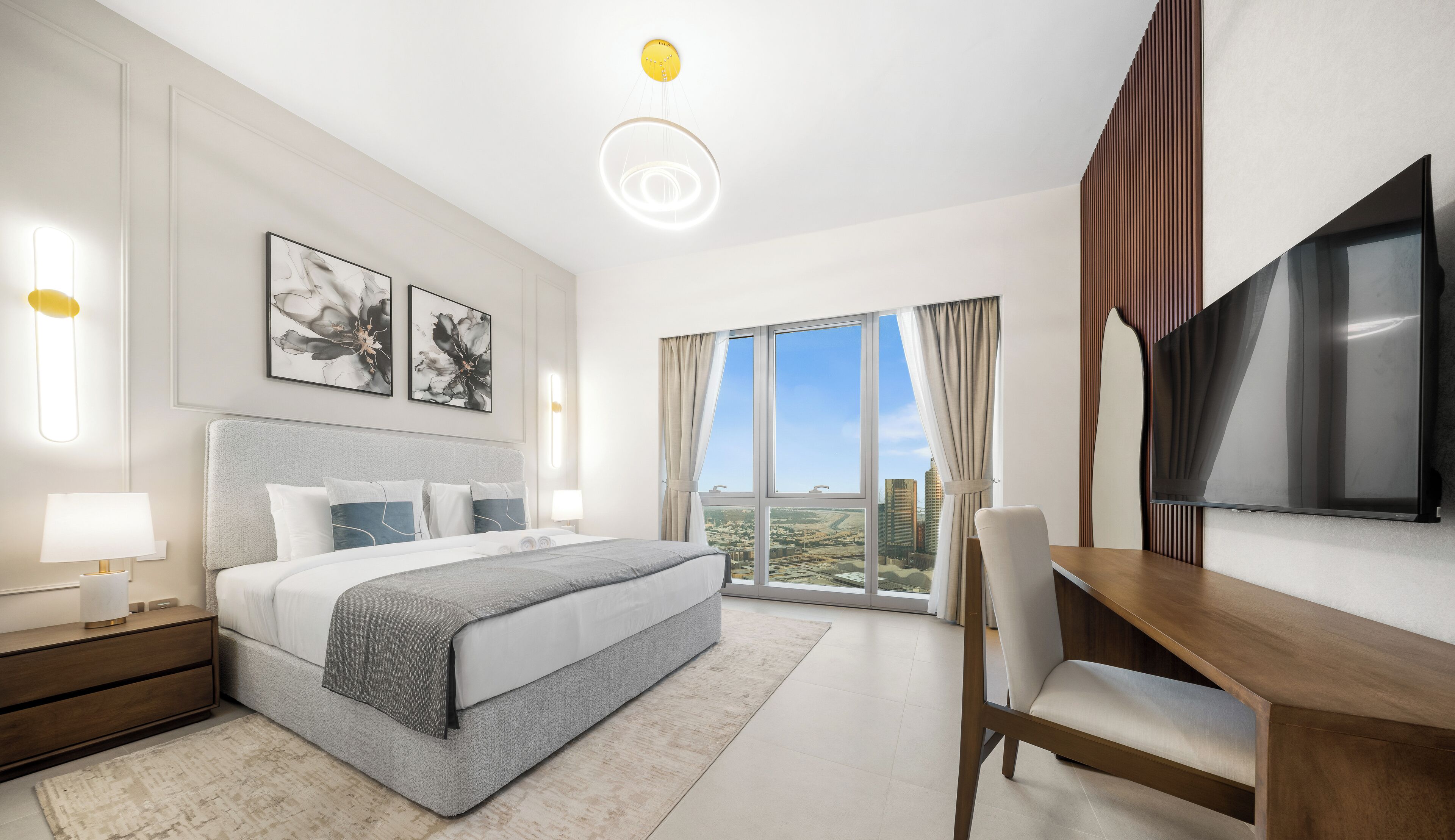A modern hotel room with a large bed, a desk, a TV, and a city view.