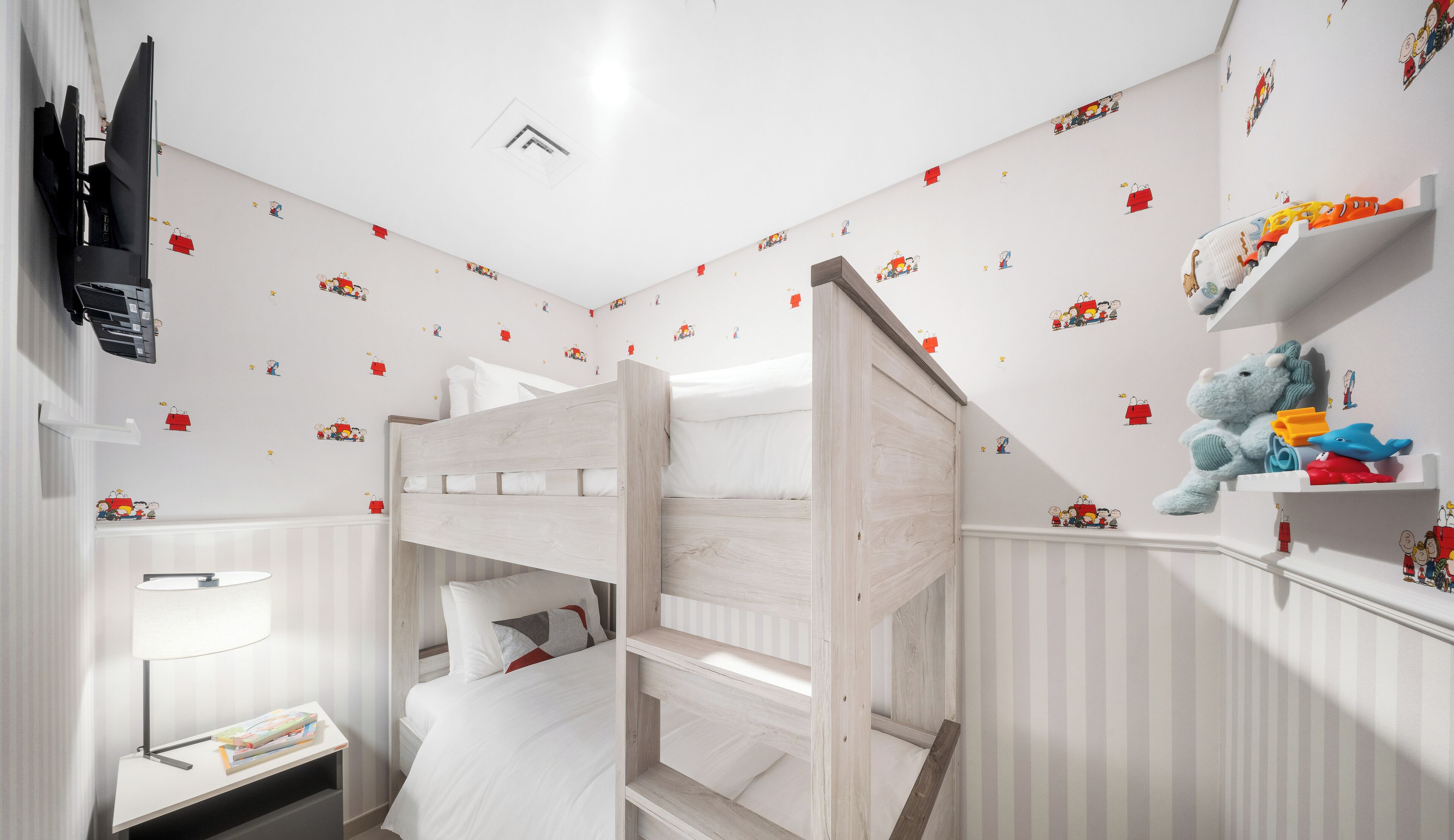 A child's bedroom with bunk beds, a TV, and wall decals.