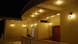 Vestíbulo de hotel con balcón curvo, varias puertas y luces fijadas a la pared.