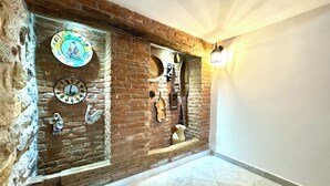 A hallway with a brick wall, decorative plates, and a tiled floor. - " Village Center Apartments - Apt 1 - 2 " (Bari Sardo)