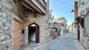A narrow street with stone buildings, a wooden door, and a metal gate. - " Village Center Apartments - Apt 1 - 2 " (Bari Sardo)
