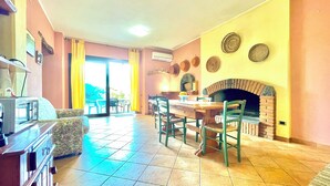 Un comedor con horno de ladrillo, una mesa, sillas y un televisor.