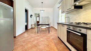 A modern kitchen with a built-in oven, a dining area with a table and chairs, and a hallway leading to another room. - "  Sea  Breeze  Home " (Lotzorai)