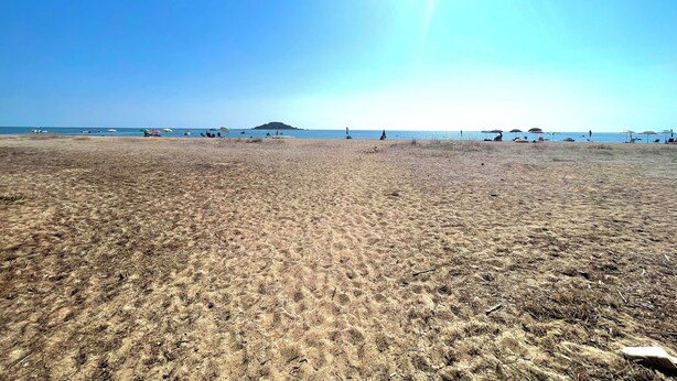 A beach with a clear sky, a sandy shore, and a distant island. - "  Sea  Breeze  Home " (Lotzorai)