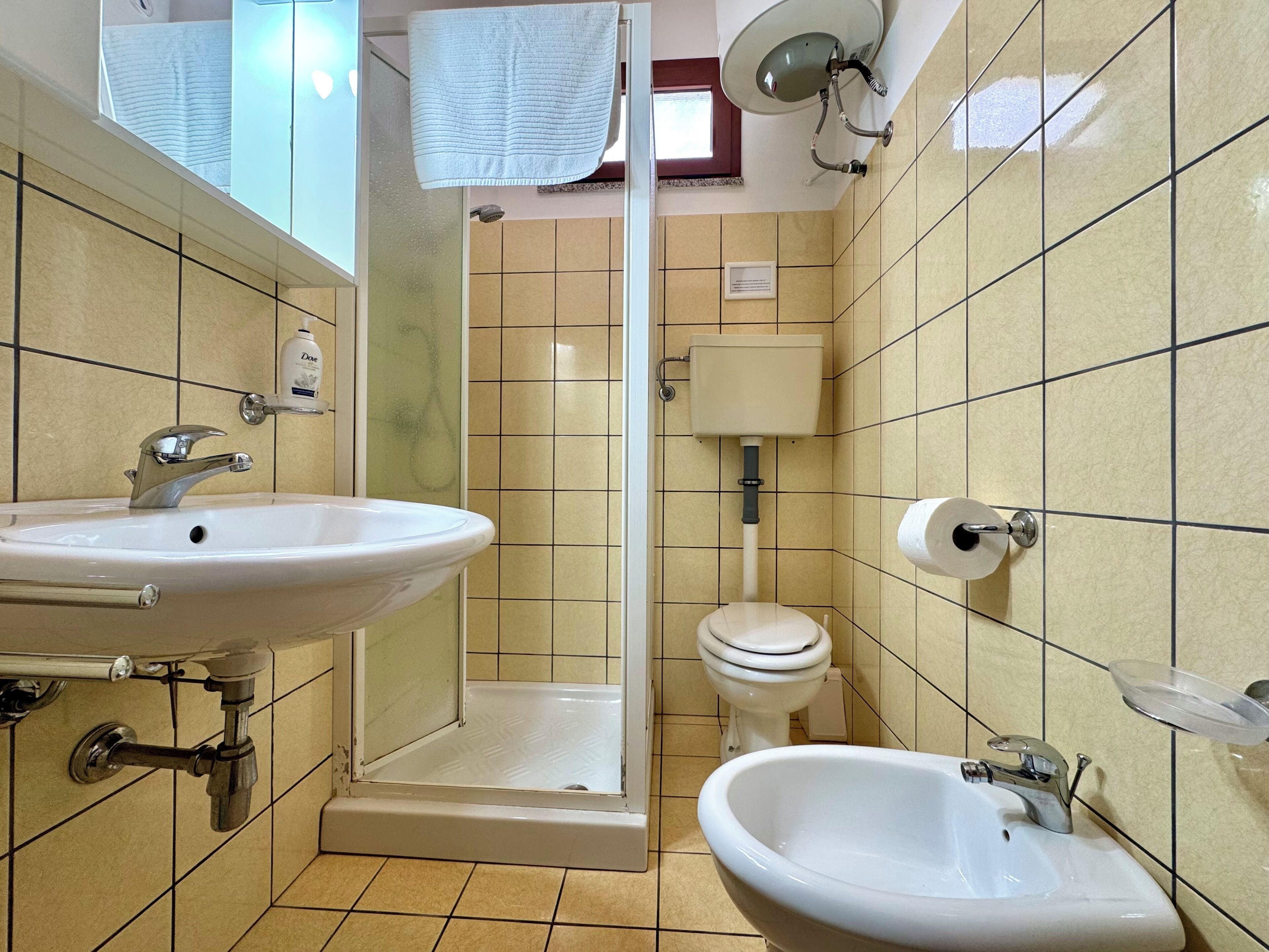 Een badkamer met douche, toilet, wastafel en bidet.