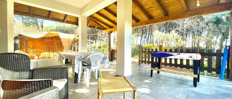 An outdoor patio with wicker furniture, a pool table, and a covered area with a table and chairs.