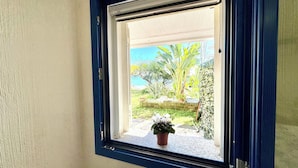 Ein Fenster mit Blick auf einen Garten und eine Steinmauer.