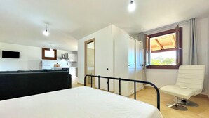 Een hotelkamer met een bed, een stoel, een bureau en een kitchenette.