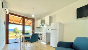 Een compact woongedeelte met een eethoek, kitchenette en een bank.