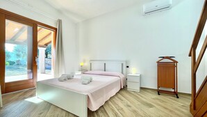 A bedroom with a bed, bedside tables, an air conditioning unit, and a wooden wardrobe. - " Cronta Apartments Deluxe with Terrace " (Bari Sardo)