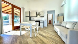 A modern living space with a dining area, kitchen, and a sofa. - " Cronta Apartments Deluxe with Terrace " (Bari Sardo)