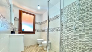 A modern bathroom with a shower, toilet, and sink. - " Cronta Apartments Deluxe with Terrace " (Bari Sardo)