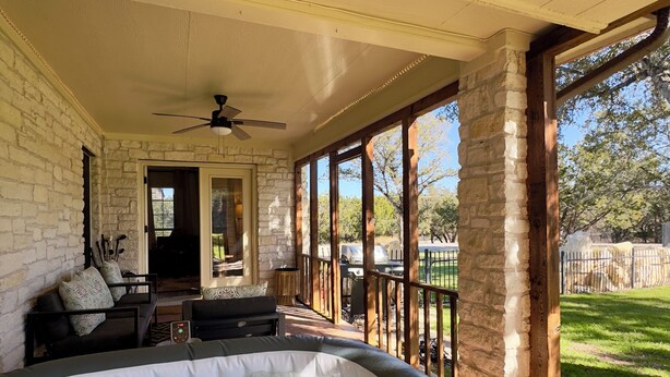 A hot tub area with a stone wall, a ceiling fan, and a view of the backyard. - Spacious Family Gem, Close to Lake, Hot Tub (Lago Vista)
