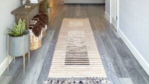 A hallway with a wooden floor, a rug, a sofa, a TV, and a fireplace. - Spacious Family Gem, Close to Lake, Hot Tub (Lago Vista)