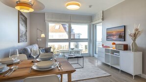 A modern living room with a dining area, large windows, and a view of the outside. - Strandperle - "Strandperle on Sylt: Your dream vacation with sea views and comfort!" (Wenningstedt-Braderup (Sylt))