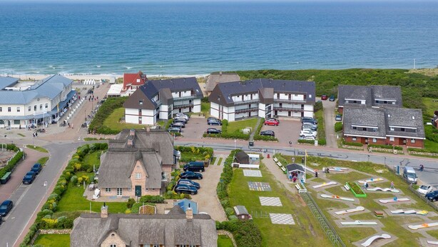 A coastal residential area with houses, a parking lot, and a beach in the background. - Strandperle - "Strandperle on Sylt: Your dream vacation with sea views and comfort!" (Wenningstedt-Braderup (Sylt))