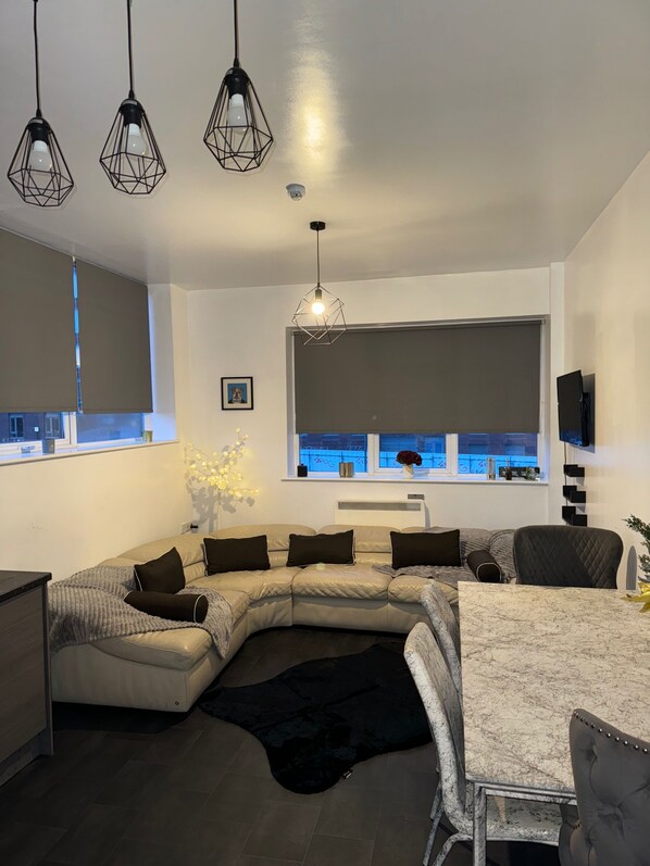 Relax in this stylish living space with a comfortable L-shaped sofa, glass dining table, and large window offering a city view.
