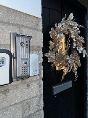 Secure entrance with a welcoming touch, featuring a keypad intercom and decorative wreath.