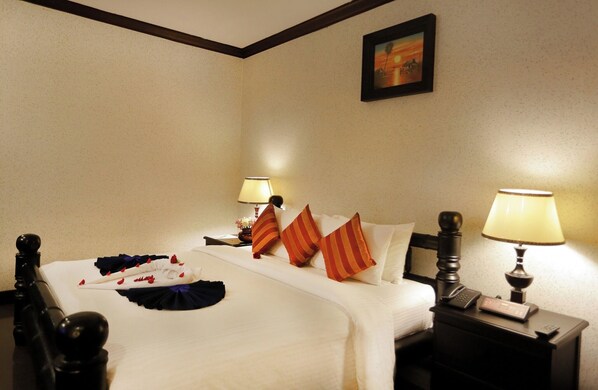 A hotel room with a neatly made bed, two bedside lamps, a nightstand with a phone, and a painting on the wall. - Lucky Angkor Hotel (Siem Reap)