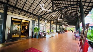 En rummelig overdækket terrasse med flisegulv, siddepladser og plantekasser.