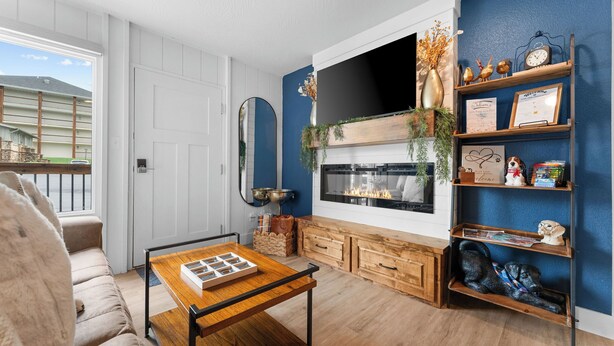 A living room with a fireplace, a TV mounted on the wall, a sofa, a coffee table, and a bookshelf.
