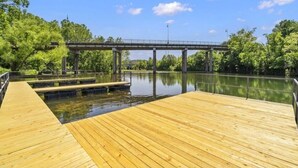 A wooden dock extending over calm water with a bridge in the background.
