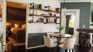 Une chambre confortable avec un lit, une table de chevet et une commode. Le sol est en bois et il y a une fenêtre avec des rideaux.