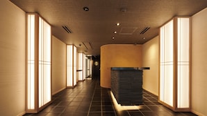 Un pasillo con paredes y suelo de madera, iluminación empotrada y un mostrador de recepción.