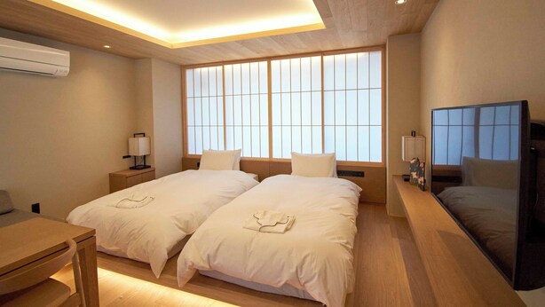 Una habitación de hotel moderna con dos camas, un escritorio y un televisor.